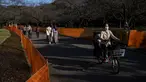 Orang-orang melewati jalan setapak di antara pagar yang ditempatkan untuk menutup bagian taman untuk mencegah pesta melihat bunga sakura (Hanami) di bawah pohon untuk pencegahan keamanan terhadap COVID-19 di salah satu tempat Hanami paling populer di Tokyo (13/3/2021).  (AP Photo/Kiichiro Sato)