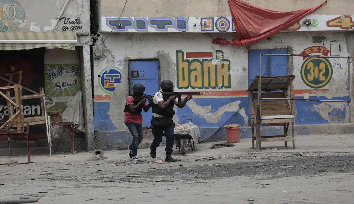 <p>Petugas polisi berlindung selama operasi anti-geng di lingkungan Portail, Port-au-Prince, sehari setelah massa di ibu kota Haiti itu menarik 13 tersangka anggota geng dari tahanan polisi lalu memukuli dan membakar mereka sampai mati. (AP Photo/Odelyn Joseph)</p>