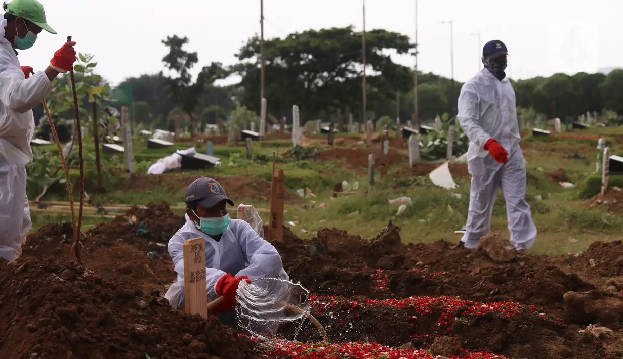 Petugas menyiram makam jenazah Covid-19 usai melakukan pemakaman dengan prosedur Covid-19 di TPU Tegal Alur, Jakarta, Minggu (3/12/2021). Sebelumnya, total kasus positif Covid-19 di Indonesia hingga Sabtu (2/12) sebanyak 758.473 kasus. (Liputan6.com/Angga Yuniar)