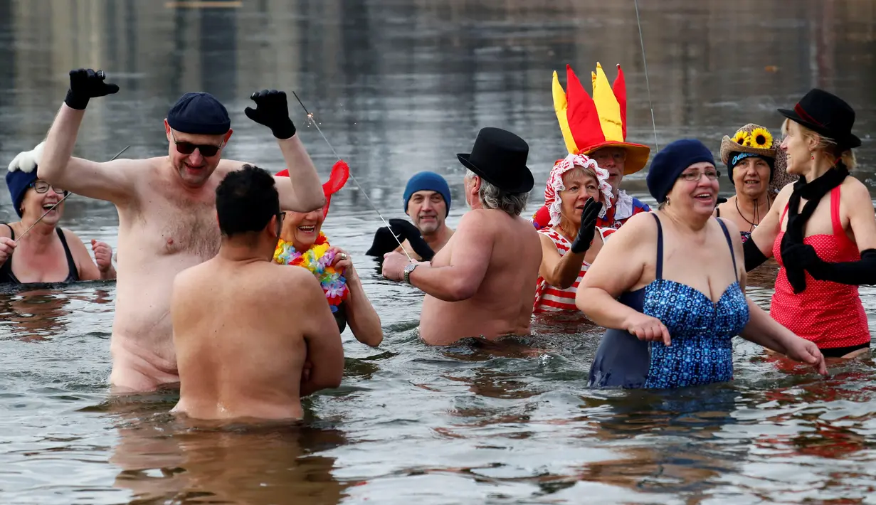 Anggota klub renang es "Berliner Seehunde" merayakan tahun baru dengan berenang di danau Orankesee, Berlin, Jerman (1/1). Selain berenang mereka juga bermain air sambil menyalakan kembang api. (REUTERS/Fabrizio Bensch)