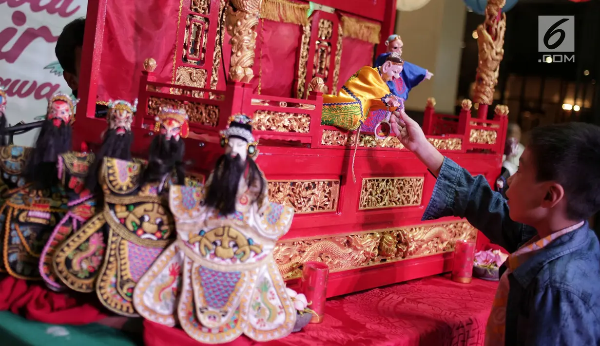Seorang anak menyaksikan pementasan wayang potehi di salah satu mall di Jakarta, Jumat (1/2). Pementasan wayang potehi  sebagai upaya untuk memperkenalkan kebudayaan Tionghoa kepada pengunjung mal. (Liputan6.com/Faizal Fanani)