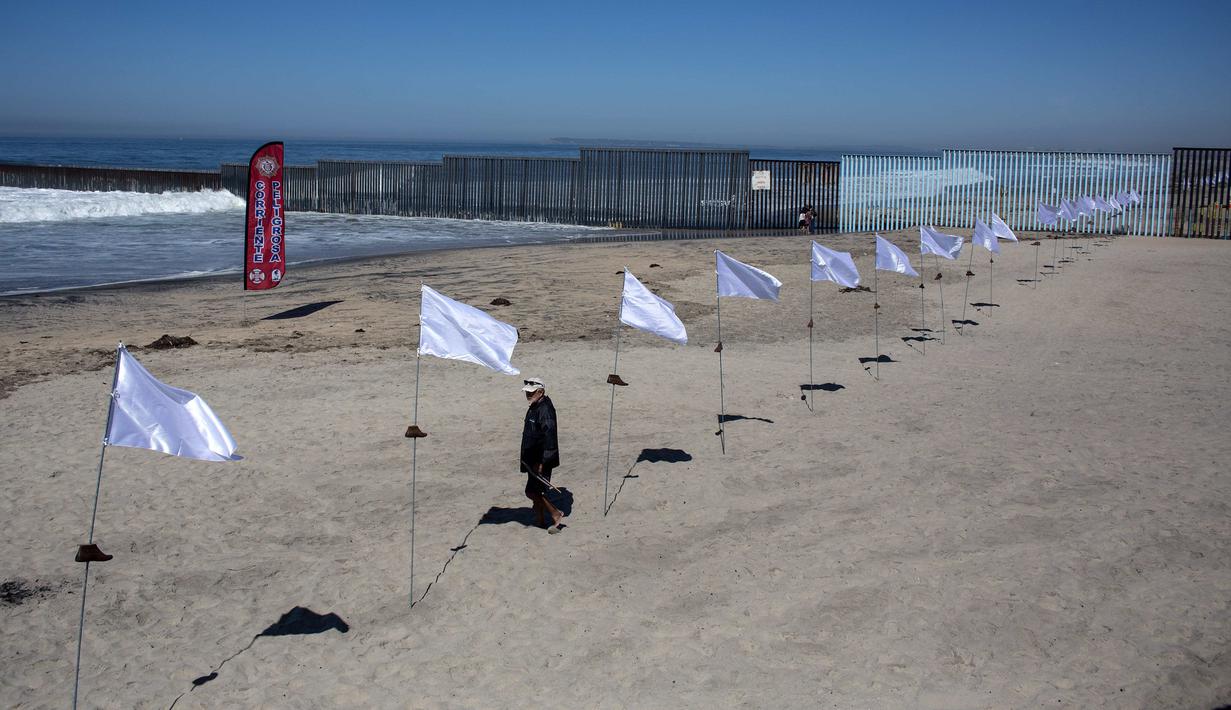 Seorang pria melintas di dekat seni instalasi kontemporer "Tu huella es el camino, tu bandera es de paz" di Playas de Tijuana, Meksiko (7/10). (AFP Photo/Guillermo Arias)