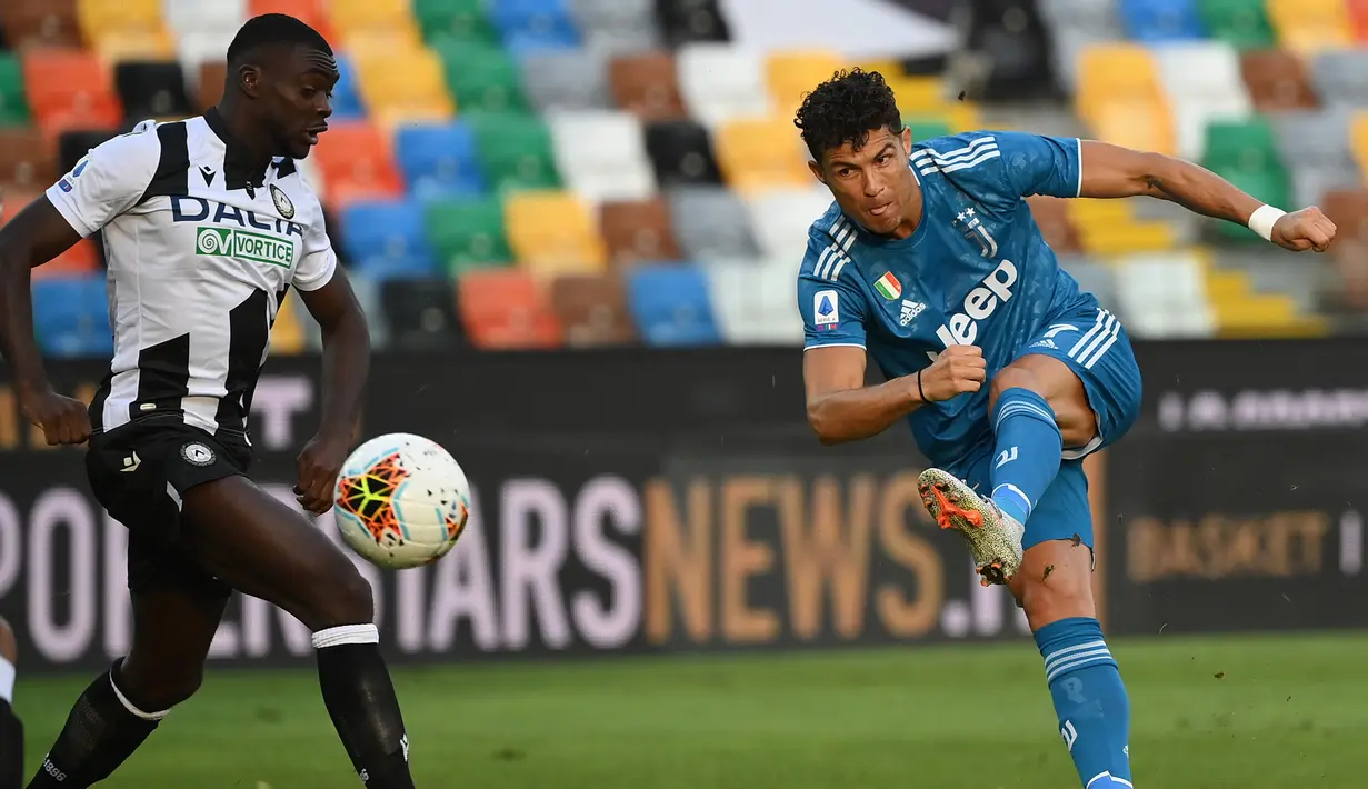 Penyerang Juventus, Cristiano Ronaldo (kanan) menendang bola saat bertanding melawan Udinese pada pertandingan lanjutan Liga Serie A Italia di Stadion Dacia Arena di Udine (23/7/2020). Juventus masih bertengger di puncak klasemen Liga Italia dengan 80 poin. (AFP Photo/Marco Bertorello)