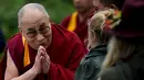 Dalai Lama menyapa salah satu penonton saat tiba di acara Glastonbury Festival, Inggirs, (28/6/2015). Dalai Lama akan berulang tahun yang ke-80 pada 6 Juli 2015 nanti. Namun ia merayakannya lebih awal di Glastonbury Festival. (REUTERS/Dylan Martinez)