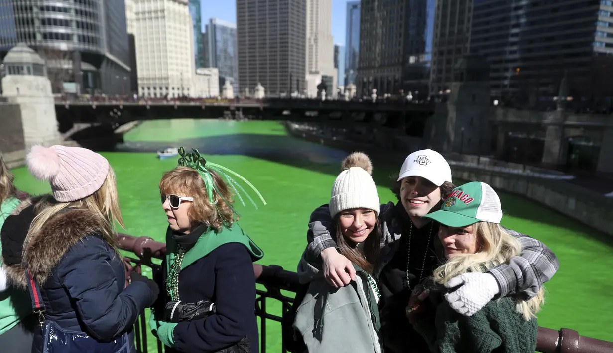 Orang-orang mengambil foto di State Street Bridge setelah pewarnaan Sungai Chicago di Chicago, Sabtu (12/3/2022). Perubahan warna ini dilakukan untuk menyambut Hari St. Patrick pada Kamis mendatang.  (John J. Kim/Chicago Tribune via AP)