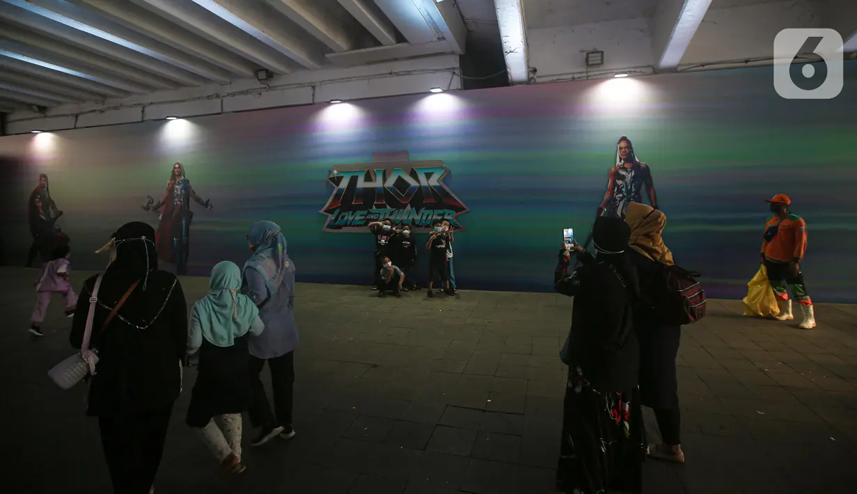 Warga foto dengan latar belakang mural kolaborasi di Terowongan Kendal, Kawasan TOD Dukuh Atas, Jakarta, Rabu (6/7/2022). Karya seni mural yang terinspirasi dari film Marvel Studios "Thor: Love and Thunder" itu memanfaatkan teknologi augmented reality (AR). (Liputan6.com/Faizal Fanani)