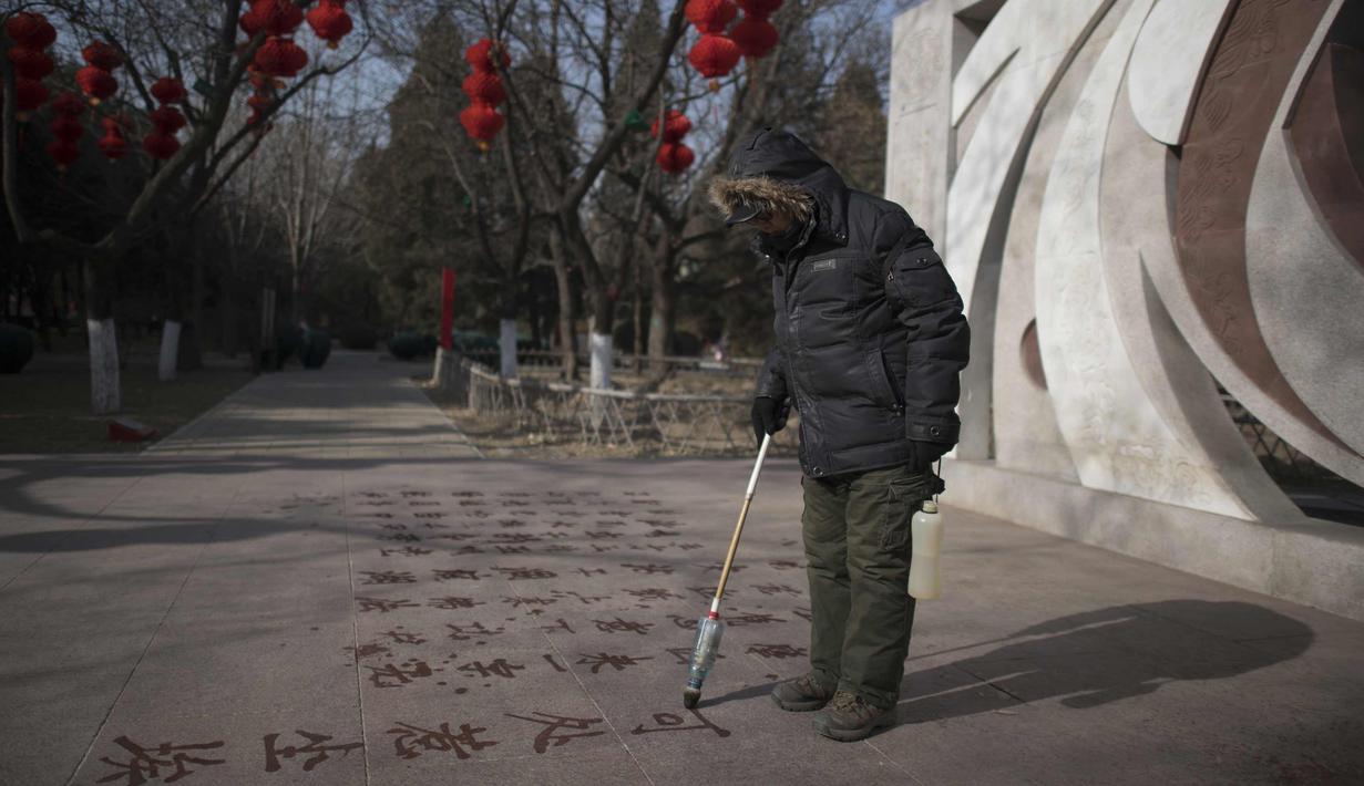 Seorang pria menulis sebuah puisi di lantai dengan air di Ditan Park di Beijing (1/2). Tahun Baru Imlek jatuh pada 16 Februari tahun ini, dengan perayaan yang berlangsung selama seminggu di China. (AFP Photo/Nicolas Asfouri)