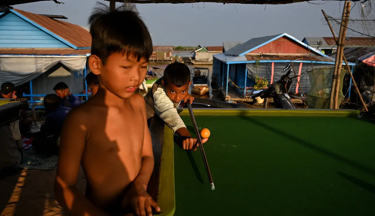 Anak-anak bermain di meja biliar di sebuah desa terapung di sepanjang sungai Siem Reap, Kamboja (5/12/2019). Sungai ini dikelilingi oleh sawah yang subur, bunga teratai, dan hutan banjir. (AFP/Manan Vatsyayana)