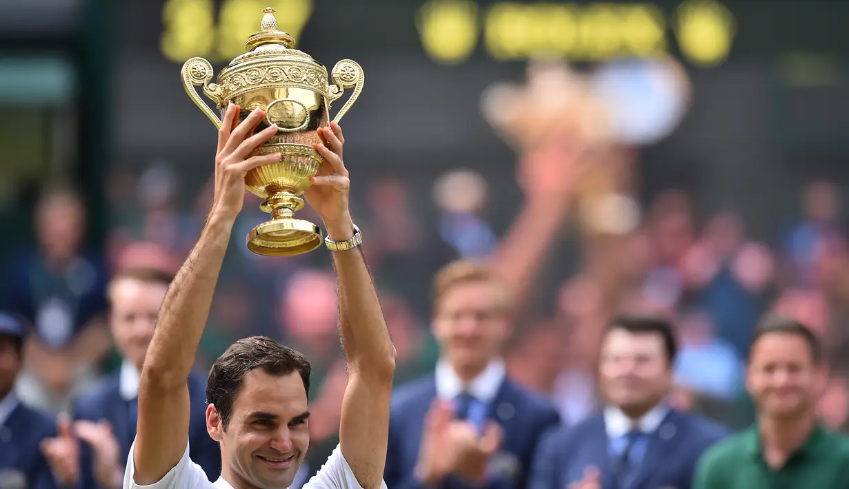 Petenis Swiss, Roger Federer mengangkat trofi kemenangan dihadapan penonton setelah mengalahkan petenis Kroasia, Marin Cilic pada pertandingan final tunggal putra Kejuaraan Wimbledon 2017 di Wimbledon, London. (16/07). (AFP Photo / Glyn Kirk)