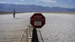 Sebuah tanda peringatan bahaya panas ekstrem di Badwater Basin, di Taman Nasional Death Valley, Taman Nasional Death Valley, California, Kamis (1/9/2022). Tempat wisata populer di California ini merupakan  salah satu tempat terpanas dan terkering yang ada di dunia.  (AP Photo/John Locher)