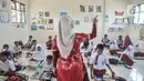 Guru saat mengajarkan para murid di salah satu kelas Sekolah Dasar Negeri (SDN) Mekarsari 05, Tambun Selatan, Kabupaten Bekasi, Jawa Barat, Kamis (28/7/2022). Sudah dua pekan berlangsung sejak dimulainya Tahun Ajaran Baru 2022 murid kelas IV dan V di SDN Mekarsari 05 mengikuti kegiatan belajar tanpa fasilitas meja dan kursi. (merdeka.com/Iqbal S. Nugroho)