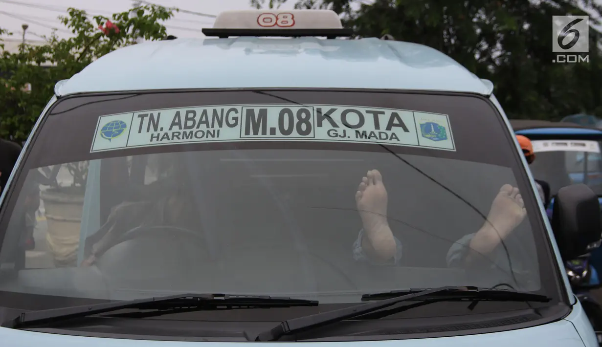 Seorang sopir angkot M08 trayek Tanah Abang-Kota tertidur di dalam kendaraannya di Jalan Jatibaru, Jakarta, Kamis (22/2). Para sopir terlihat sedang menunggu rekan sopir M03 dan M10 yang juga akan ikut berunjuk rasa. (Liputan6.com/Arya Manggala)