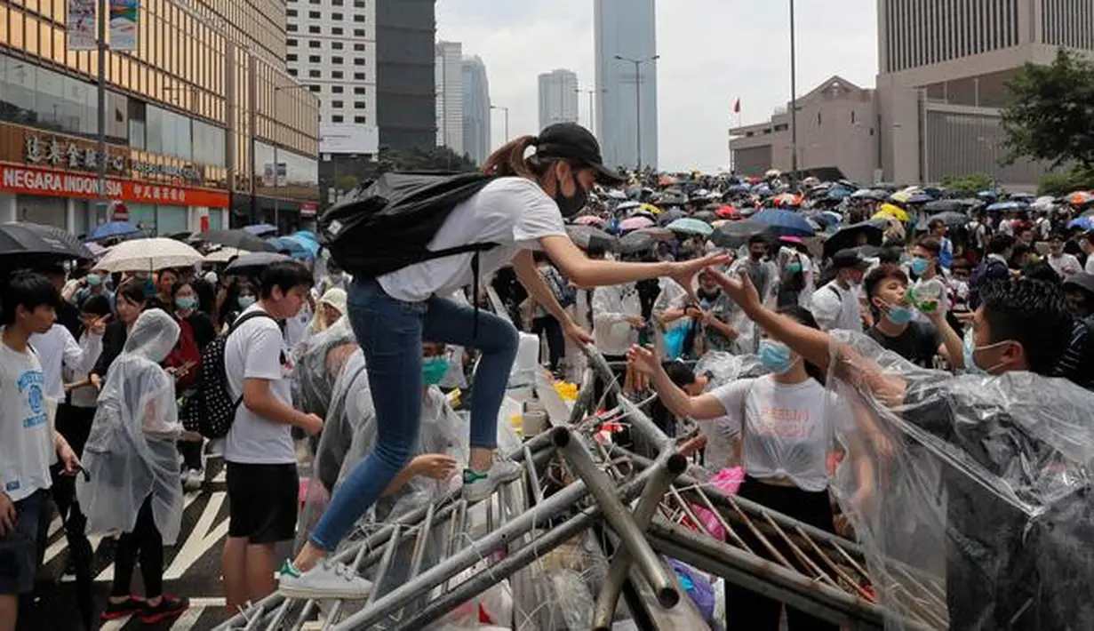 Seorang wanita memanjat paga saat bentrok dengan polisi anti huru hara di luar gedung Dewan Legislatif, Hong Kong, Rabu (12/6/2019). Polisi Hong Kong telah menggunakan gas air mata ke arah ribuan demonstran yang menentang RUU ekstradisi yang sangat kontroversial. (AP Photo/ Kin Cheung)