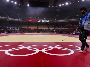 Petugas membersihkan dan mendisinfektan matras sebelum hari kelima kompetisi judo Olimpiade Tokyo 2020 di Nippon Budokan di Tokyo pada Rabu (28/7/2021). Olimpiade yang digelar saat pandemi COVID-19 tersebut menerapkan protokol kesehatan ketat. (Jack GUEZ / AFP)