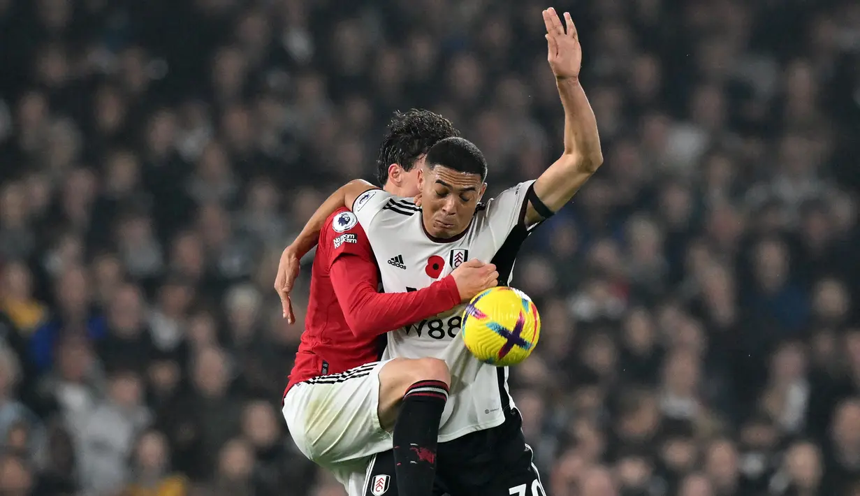 Bek Manchester United (MU), Victor Lindelof (kiri) bersaing dengan striker Fulham Carlos Vinicius pada pekan ke-16 Liga Inggris 2022/2023 di Craven Cottage, London, Minggu (13/11/2022). MU berada di peringkat ke-5 dengan 26 poin dan tertinggal tiga poin di belakang Tottenham. (Photo by Glyn KIRK / AFP)