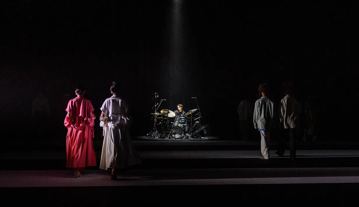 Seorang musisi memainkan durm sebagai model yang menampilkan kreasi dari brand fashion Hare selama koleksi musim semi / musim panas 2021 di Tokyo Fashion Week (15/10/2020). (AFP Photo/Philip Fong)
