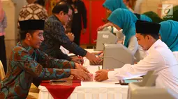 Presiden Joko Widodo (kiri) menyerahkan zakat mal kepada petugas Badan Amil Zakat Nasional (Baznas) di Istana Negara, Jakarta, Kamis (16/5/2019). Jokowi menyerahkan zakat penghasilan senilai Rp 55 juta secara tunai. (Liputan6.com/Angga Yuniar)