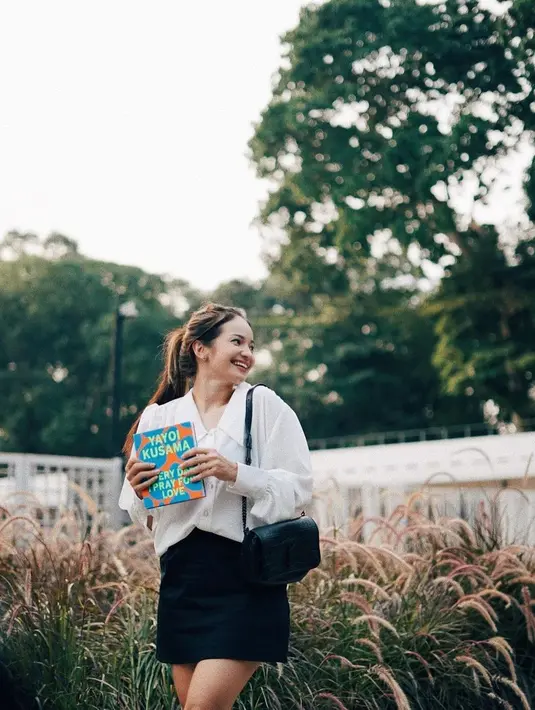 Enzy Storia juga rasanya tak pernah gagal tampil mengenakan outfit apapun. Lihat bagaimana Enzy menikmati harinya dengan membaca buku mengenakan atasan kemeja putih, dipadu dengan mini skirt hitam, tampilan chic untuk acara kasual. [Foto: Instagram/enzystoria]