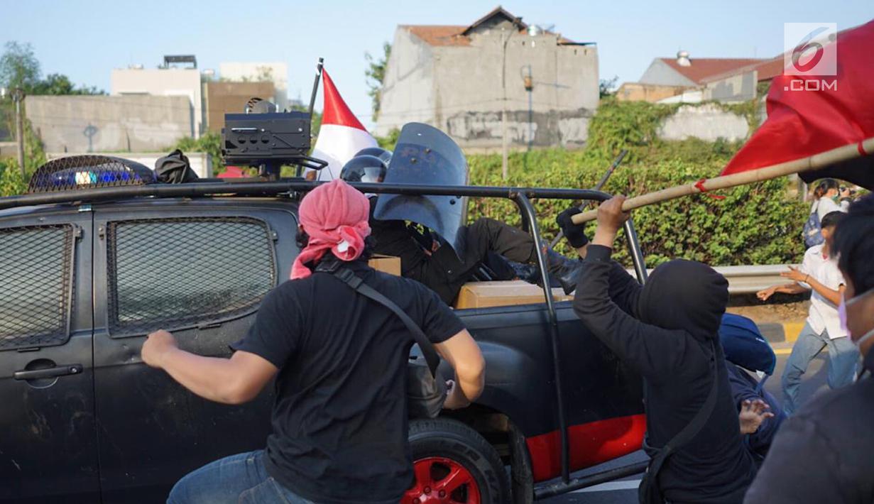Aparat kepolisian berlindung di balik tameng saat kendaraan yang dinaiki diserang massa pelajar dalam unjuk rasa di sekitar kawasan DPR RI, Jakarta, Senin (30/9/2019). Sempat terjadi kericuhan akibat peristiwa tersebut hingga menyebabkan jalan tol ditutup. (Liputan6.com/Immanuel Antonius)