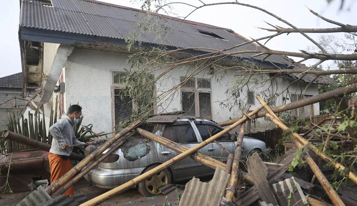 Warga memeriksa kerusakan di rumahnya di daerah yang terkena dampak letusan Gunung Semeru di Lumajang, Jawa Timur, Minggu (5/12/2021). Gunung Semeru memuntahkan kolom tebal abu, gas yang membakar dan lava menuruni lerengnya dalam letusan tiba-tiba yang dipicu oleh hujan lebat. (AP Photo/Trisnadi)