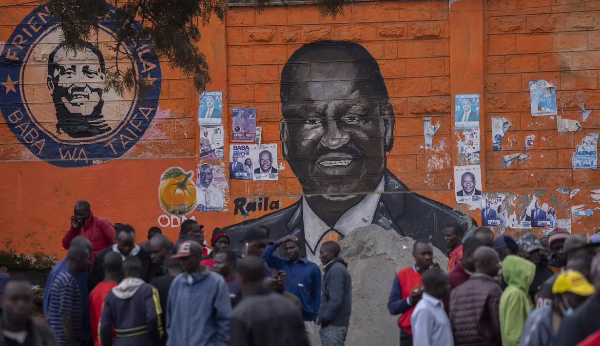 Warga berkumpul untuk membahas pemilu di depan mural calon presiden Raila Odinga, di daerah Kibera, Nairobi, Kenya, Kamis, 11 Agustus 2022. Rakyat Kenya menunggu hasil pemilihan presiden yang berlangsung ketat namun tenang di mana jumlah pemilih lebih rendah daripada biasanya. (AP Photo/Ben Curtis)