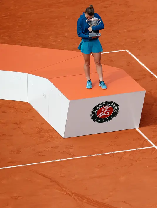 Petenis Rumania, Simona Halep mencium trofi Grand Slam seusai menang atas Sloane Stephens dari AS pada babak final Prancis Terbuka 2018 di Roland Garros, Sabtu (9/6). Halep sukses menyabet gelar Grand Slam perdana sepanjang kariernya. (AP/Thibault Camus)