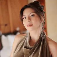 Dipermanis dengan anting menjuntai dan handbag warna silver yang selaras. [@sharazaaa]