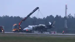 Alat berat mengangkat pesawat Cessna 560XL yang terbakar saat mendarat di Bandara Aarhus di Tirstrup (6/8/2019). Pesawat terbakar akibat roda mogok saat ingin mendarat dan pesawat mulai miring dan kebakaran terjadi di sisi kiri pesawat. (Oexenholt Foto/Ritzau Scanpix/AFP)