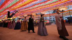 Biksu dan pengikutnya mengenakan masker sambil menjaga jarak sosial sebagai pencegahan terhadap virus corona membawa lampion di kuil Jogye, Seoul, Korea Selatan (6/5/2021). Warna-warni lampion dipasanga untuk merayakan ulang tahun Buddha yang akan datang pada 19 Mei. (AP Photo/Lee Jin-man)