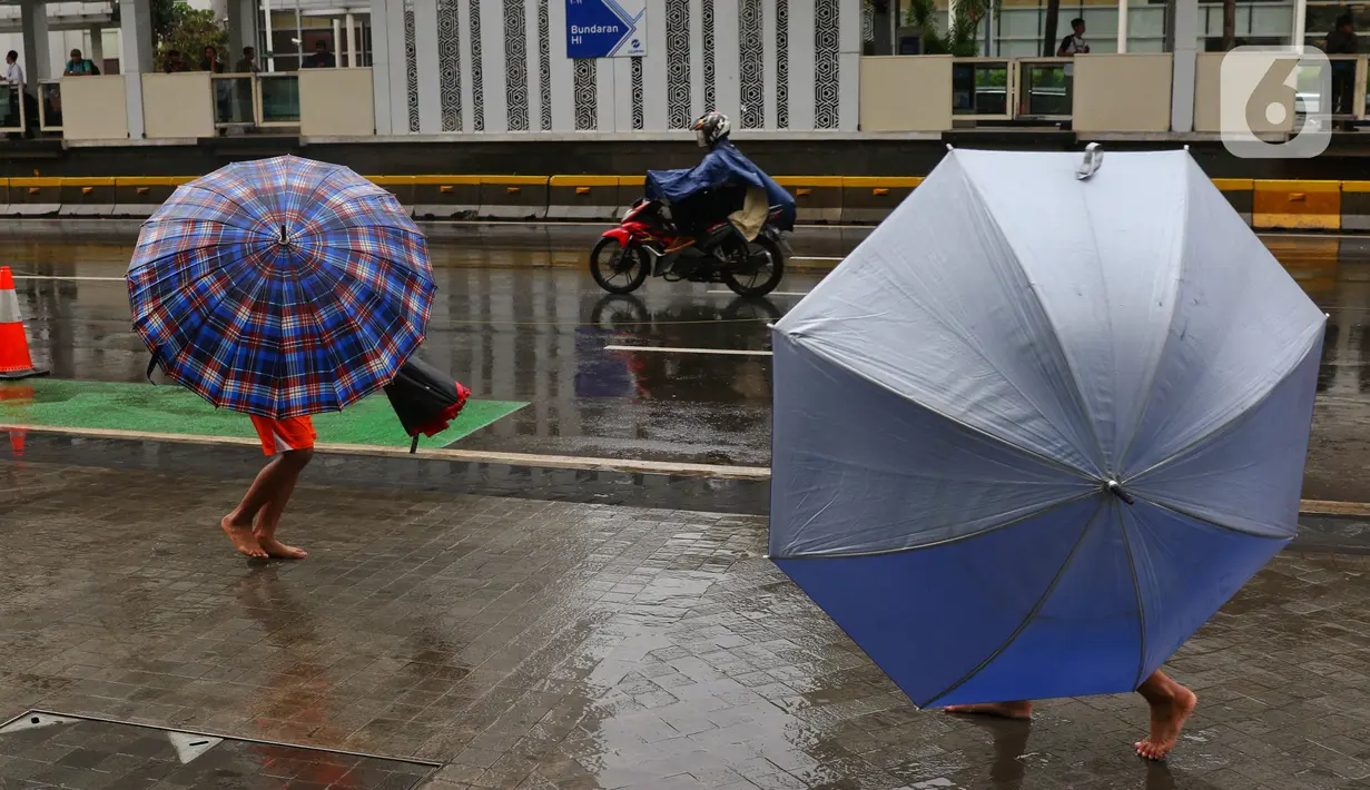 Sejumlah anak-anak menawarkan jasa ojek payung kepada warga di kawasan Bundaran HI, Jakarta, Senin (3/2/2020). Hujan deras yang mengguyur sejumlah wilayah di DKI Jakarta dimanfaatkan para pengojek payung untuk mencari penghasilan tambahan. (Liputan6.com/Angga Yuniar)