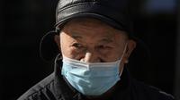 Seorang pria mendongak sambil mengenakan topeng di jalan Beijing, China, Selasa (14/12/2021). Media pemerintah China mengatakan Senin, 13 Desember 2021, kasus pertama varian omicron COVID-19 telah terdeteksi di daratan negara di kota Tianjin di sebelah timur Beijing. (AP Photo/Ng Han Guan)