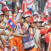 Siswa-siswi SD membawa bendera negara peserta Asian Games 2018 untuk menyambut Kirab Obor di kawasan Jati Padang, Pasar Minggu, Rabu (15/8). Mereka memenuhi jalanan untuk menyaksikan langsung Pawai Obor Asian Games 2018. (Liputan6.com/Faizal Fanani)