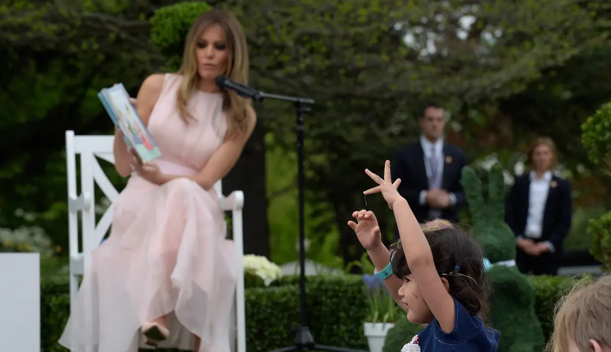 Seorang anak bermain di depan Melania Trump yang sedang membacakan cerita anak saat perayaan Paskah ke-139 di halaman selatan Gedung Putih, Washington, Senin (17/4). (AP Photo/Carolyn Kaster)