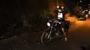 Pengendara motor mengangkat tangan saat dihentikan oleh petugas dalam operasi di Los Teques, negara bagian Miranda, Venezuela, 20 Maret 2021 Di Miranda ada aturan memakai masker serta mencegah pertemuan lebih dari lima orang, di tengah gelombang kedua pandemi COVID-19. (Federico PARRA/AFP)
