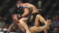 Khabib Nurmagomedov berusaha mengunci Dustin Poirier dalam pertarungan UFC 242 di Mal Yas di Abu Dhabi, Uni Emirat Arab (7/9/2019). habib sukses menang setelah kuncian lehernya memaksa Dustin melakukan tap out. (AP Photo/ Mahmoud Khaled)