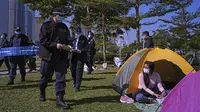 Petugas polisi membawa spanduk yang menunjukkan jarak sosial untuk mencegah penyebaran virus corona kepada pengunjung di sebuah taman di Hong Kong, Sabtu (2/1/2021). Diketahui, varian baru virus corona Inggris ditemukan di Hong Kong. (AP Photo/Vincent Yu)