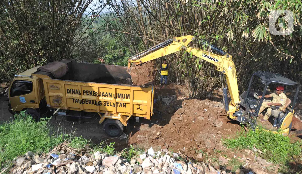 Petugas menggunakan alat berat backhoe membersihan jalan dari longsoran tanah di RT 04/RW 03, Kademangan, Keranggan, Setu, Tangerang Selatan, Banten, Selasa (3/12/2019). Longsor pada Senin sore kemarin menewaskan seorang pengendara sepeda motor yang melintas, Anggi (23). (merdeka.com/Arie Basuki)
