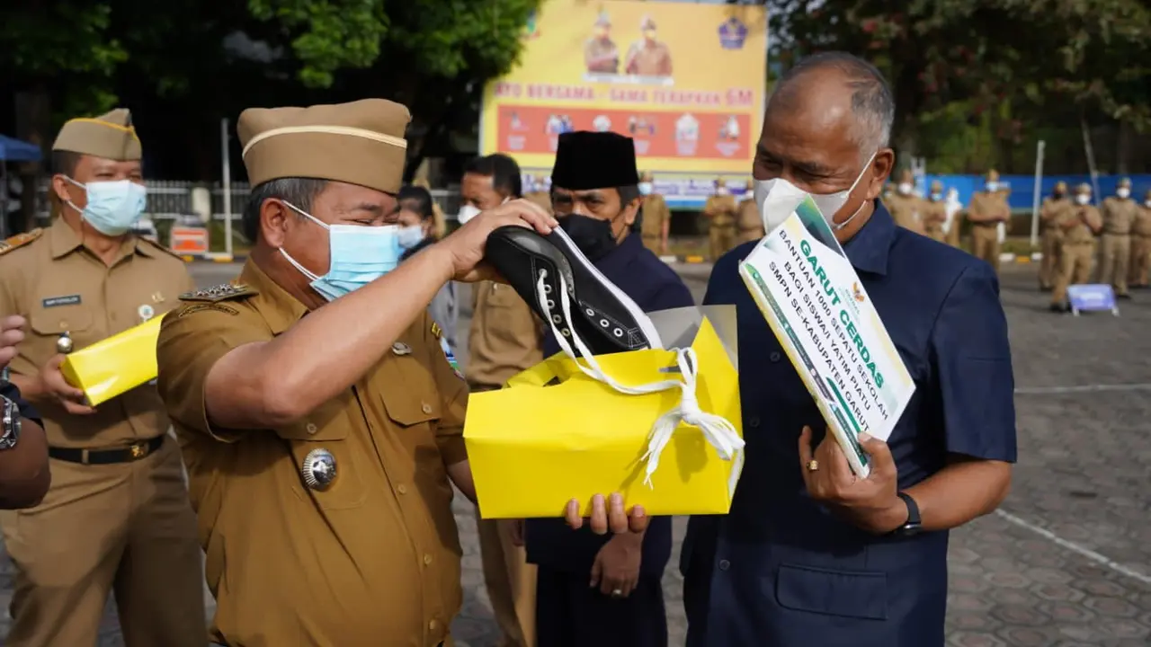 Bupati Garut Rudy Gunawan menunjukan sekaligus menyerahkan bantuan sepatu bagi pelajar yatim piatu tingkap SMP yang diterima kepala sekolah secara simbolis.