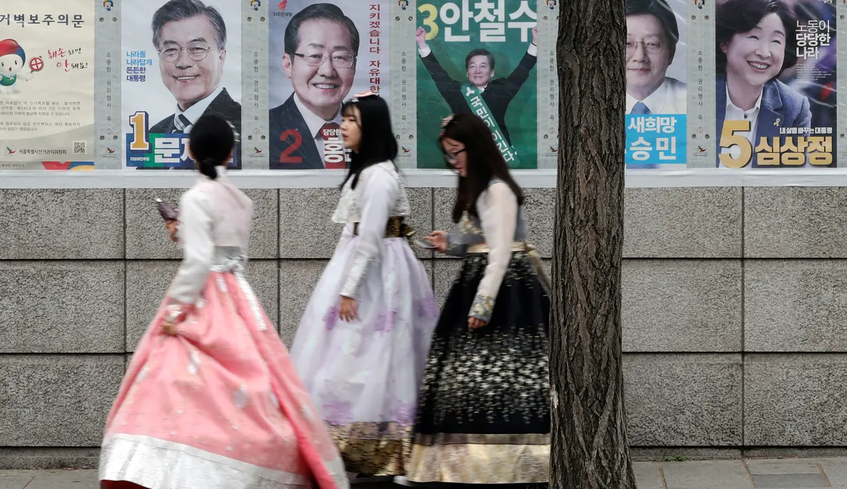 Sejumlah wanita berjalan dekat poster calon presiden Korea Selatan (Korsel) di Seoul, Selasa (9/5). Hari ini, warga Korsel mulai memberikan hak suaranya untuk memilih presiden baru setelah pemakzulan Park Geun-hye. (Jeon Heon-kyun/Pool Photo via AP)