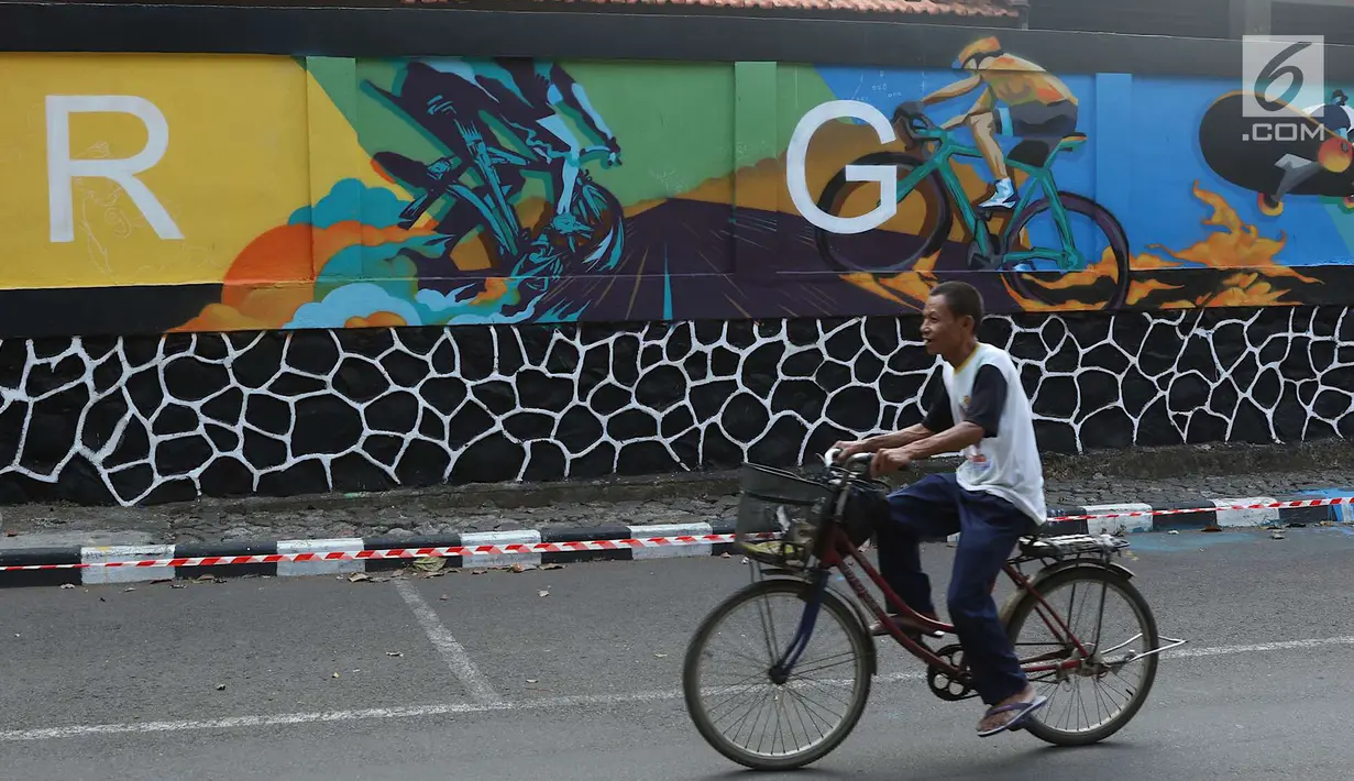Seorang pria bersepeda melintas di depan mural bertema Asian Games 2018 di kawasan Universitas Negeri Jakarta, Kamis (16/8). Mural karya mahasiswa seni rupa tersebut dibuat dalam rangka menyambut Asian Games 2018. (Liputan6.com/Immanuel Antonius)
