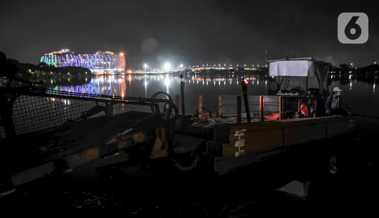Warga memancing di Waduk Cincin dengan latar belakang Jakarta International Stadium (JIS), Papanggo, Jakarta Utara, Rabu (16/3/2022). PT Jakarta Propertindo (Jakpro) menargetkan pembangunan JIS rampung dan siap dibuka pada April 2022. (merdeka.com/Iqbal S. Nugroho)
