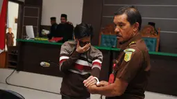 Terdakwa pasangan sejenis (gay) diborgol usai menjalani sidang di pengadilan syariah di Banda Aceh (17/5). Terdakwa dikenakan ancaman 100 kali cambuk atau denda 1.000 gram emas murni, atau 100 bulan penjara. (AFP/Chaideer Mahyuddin)