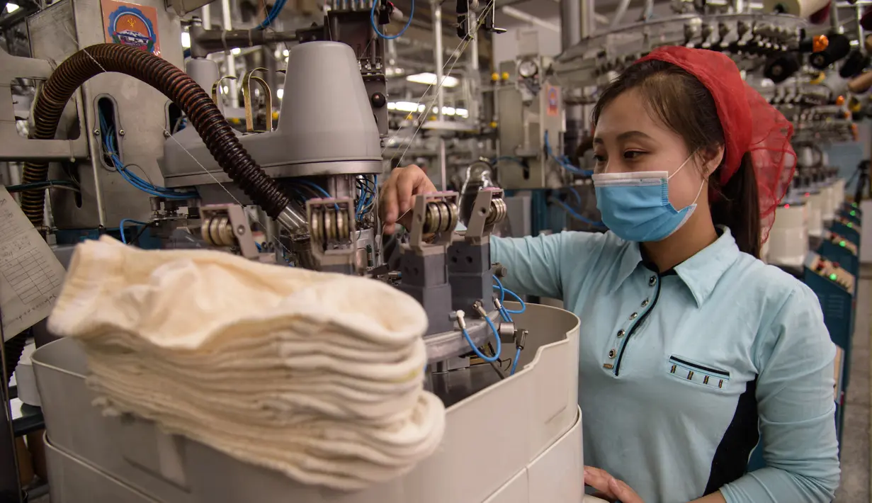 Seorang pekerja wanita saat berkerja di jalur produksi yang membuat kaus kaki pria di Pabrik Kaus Kaki Pyongyang di Korea Utara (24/5/2021). Pabrik ini memproduksi kaus kaki dengan menggunakan benang rayon Tetron domestik dan serat. (AFP/Kim Won Jin)