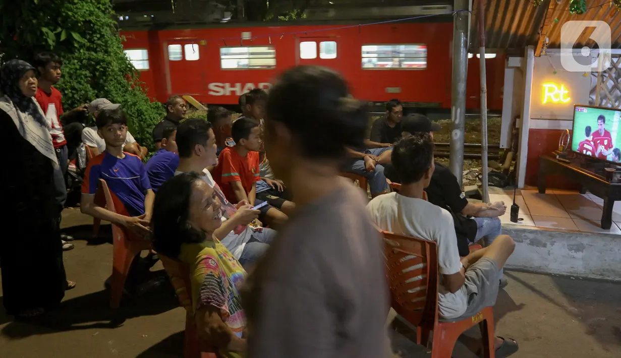 Sejumlah warga kawasan Menteng Jaya menyaksikan pertandingan sepak bola antara Timnas Indonesia melawan Bahrain pada laga Kualifikasi Piala Dunia 2026 putaran ketiga Zona Asia yang digelar di Stadion Utama Gelora Bung Karno, Jakarta, Selasa (25/3/2025). (Liputan6.com/Herman Zakharia)