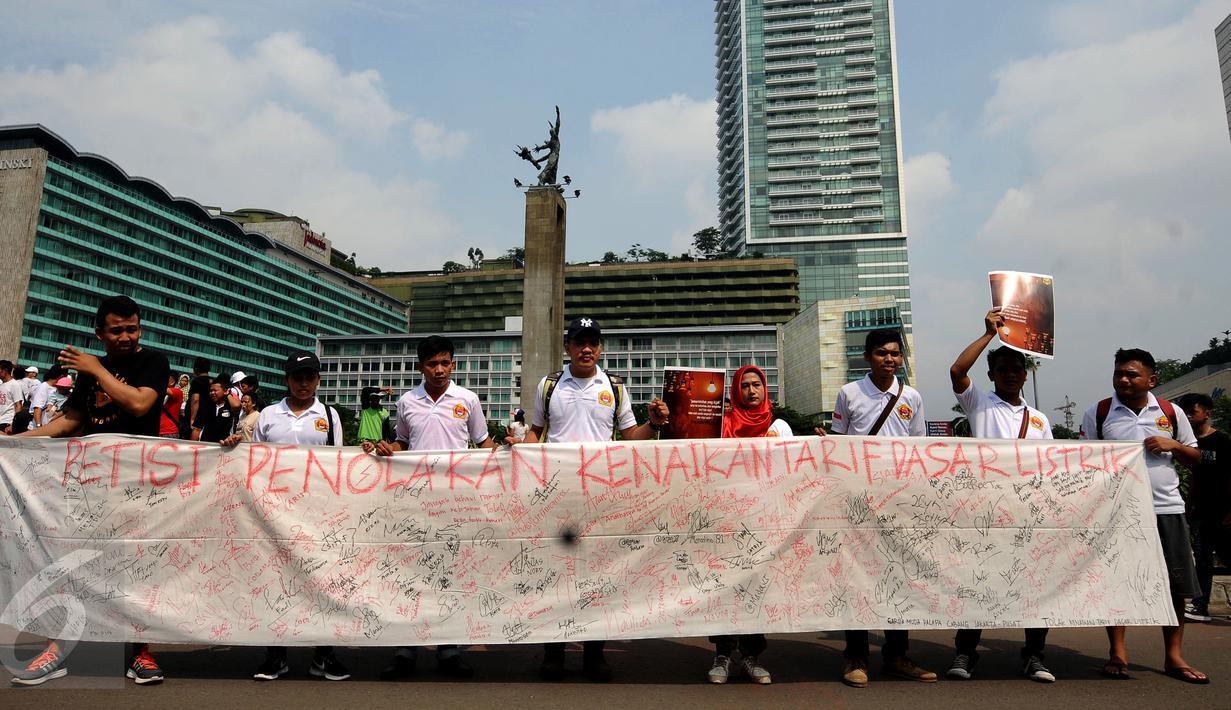 Sekelompok warga membentangkan Petisi Penolakan Kenaikan Tarif Dasar Listrik di kawasan Bundaran HI, Jakarta, Minggu (7/5). Mereka meminta pihak berwenang mengkaji kembali kebijakan kenaikan tarif dasar listrik. (Liputan6.com/Helmi Fithriansyah)