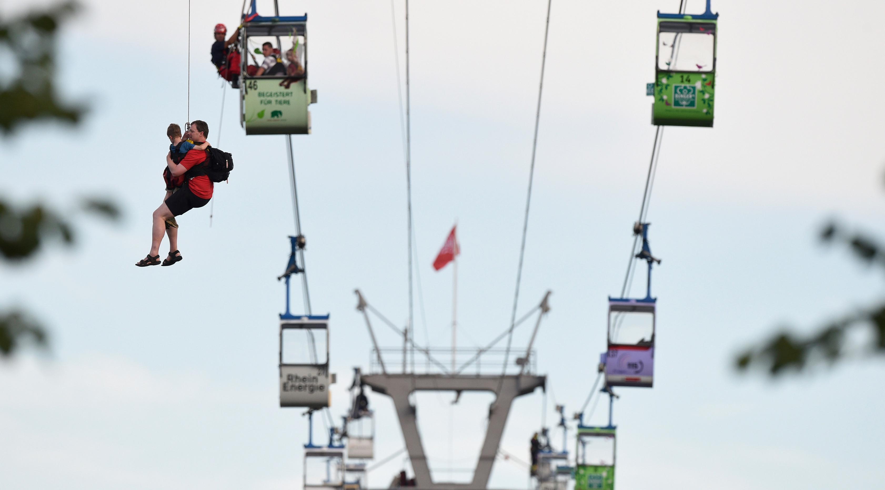 Tim pemadam kebakaran mengevakuasi penumpang kereta gantung yang terjebak di udara di Kota Koln, Jerman, Minggu (30/7). Setidaknya 100 orang terjebak setelah kereta gantung yang ditumpanginya menabrak tiang dan mendadak terhenti (Rainer Jensen/dpa via AP)