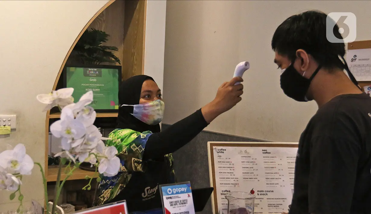 Barista mengecek suhu tubuh tamu Sunyi House of Coffee and Hope, Jakarta, Jumat (15/1/2021). Rumah kopi ini muncul atas ketertarikan untuk memperjuangkan teman-teman difabel. (Liputan6.com/Herman Zakharia)