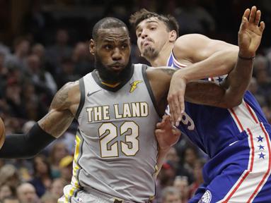 Aksi pemain Cleveland Cavaliers, LeBron James #23 melewati adangan pemain Philadelphia 76ers, Dario Saric #9 pada laga NBA basketball game di Quicken Loans Arena, Cleveland,  (1/2/2018).  Cavs kalah 97-108. (AP /Tony Dejak)