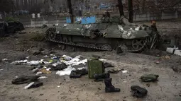 Perlengkapan militer yang ditinggalkan tentara Rusia berserakan di dekat sebuah tank saat dilakukan penyisiran militer oleh tentara Ukraina setelah penarikan pasukan Rusia dari daerah di pinggiran Kiev, Ukraina, Jumat, 1 April 2022. (AP Photo/Rodrigo Abd)