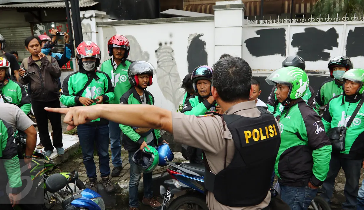 Petugas saat memberikan arahan kepada pengemudi Go-Jek yang diamankan di kawasan Senayan, Jakarta Pusat, Selasa (22/3). Mereka diamankan karena diduga akan melakukan aksi balasan terhadap Sopir Taksi.(Liputan6.com/Fery Pradolo)